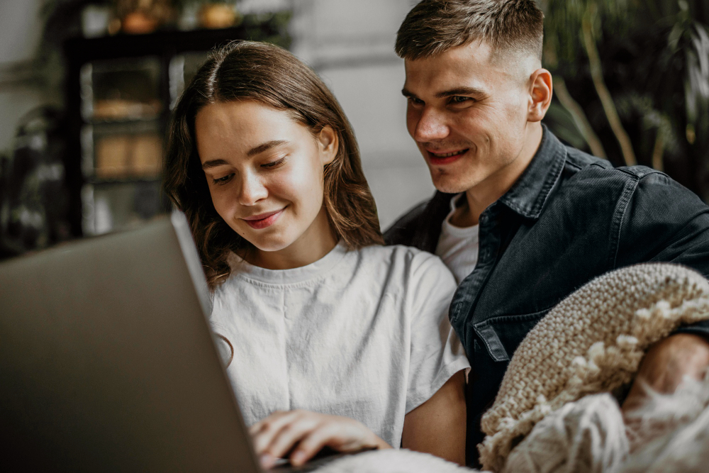jeune couple devant un ordinateur sur le canapé
