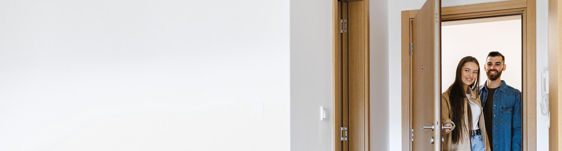 Un homme et une femme se tiennent à l’entrée d’un appartement, la porte est ouverte