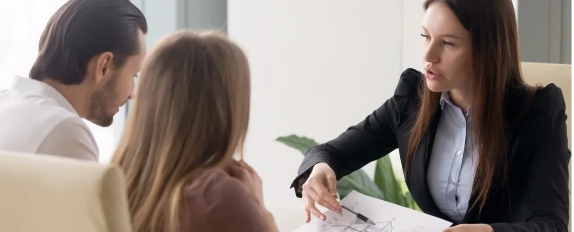 Personne présentant un document à un couple dans un bureau lumineux.