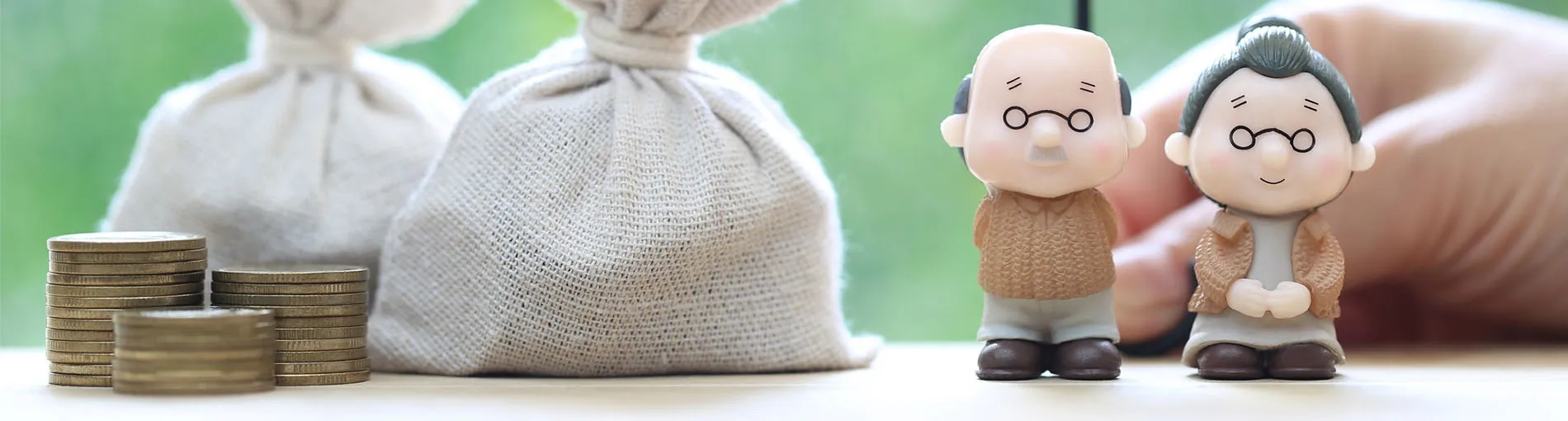 Figurines de personnes âgées avec pièces et sacs d’argent en arrière-plan.