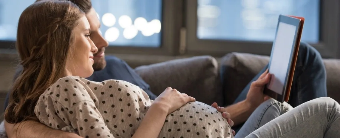 Un couple, la femme enceinte, regardent leur tablette