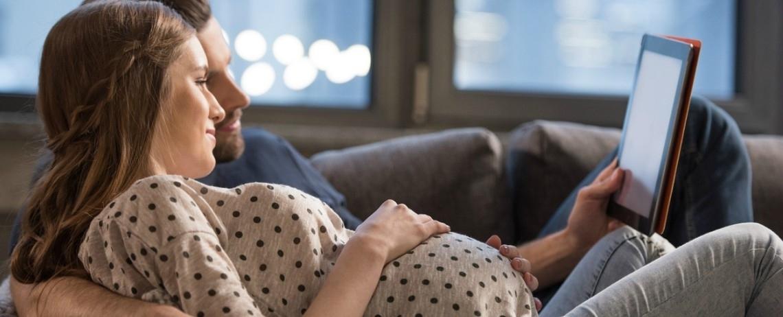 Un couple, la femme enceinte, regardent leur tablette