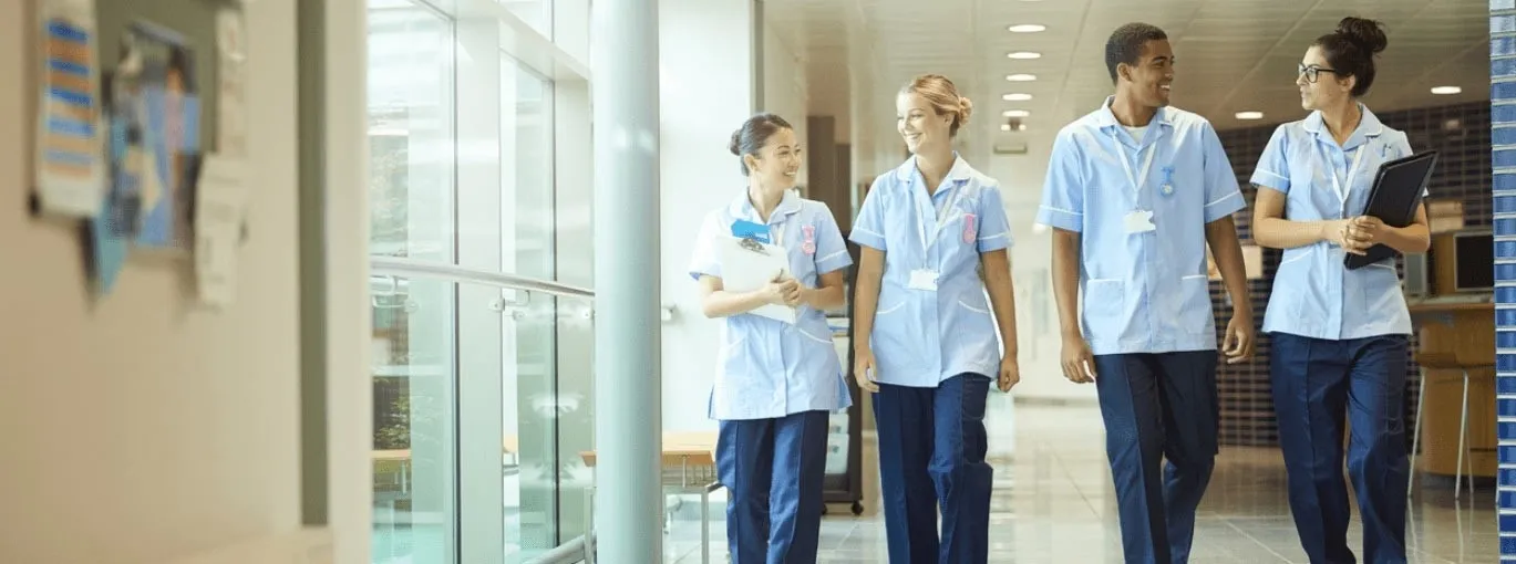 Personnel hospitalier en tenue professionnelle marchant dans un couloir.