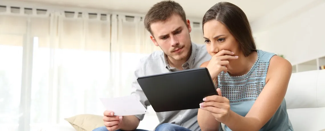 Deux personnes assises regardent une tablette, l’une tenant un document.