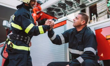 Deux pompiers se serrant la main devant un véhicule de secours.