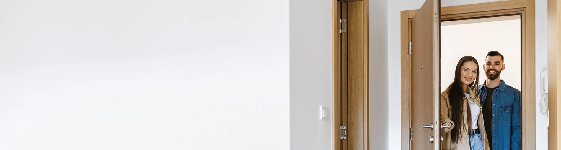Un homme et une femme se tiennent à l’entrée d’un appartement, la porte est ouverte