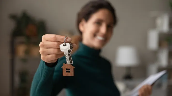 une jeune femme heureuse montre les clés de son nouveau bien immobilier