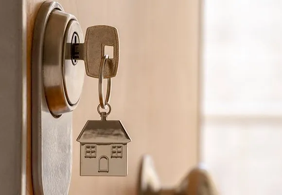 Porte‑clés maison suspendu à une clé dans une serrure