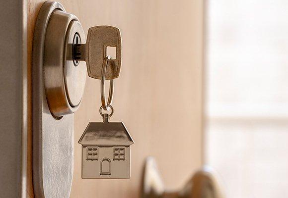 Porte‑clés maison suspendu à une clé dans une serrure