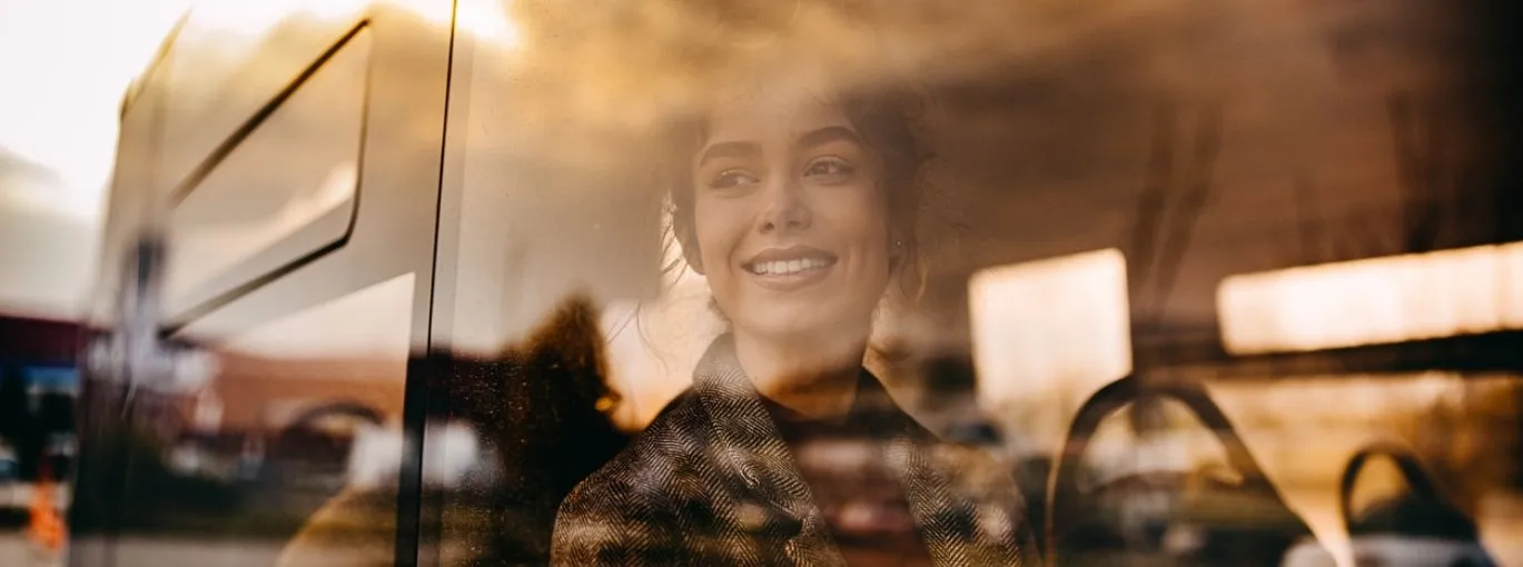 Personne regardant par la fenêtre d’un véhicule, reflet urbain visible.