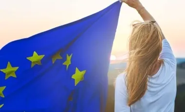 femme de dos portant un drapeau de l'Europe an vent sur son côté gauche