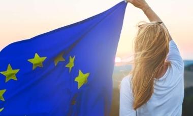 femme de dos portant un drapeau de l'Europe an vent sur son côté gauche