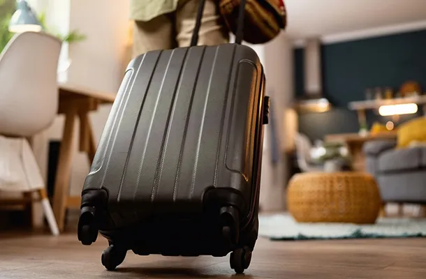 homme tire sa valise dans son salon, prêt pour son départ 