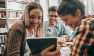 3 personnes souriantes regardant une tablette.