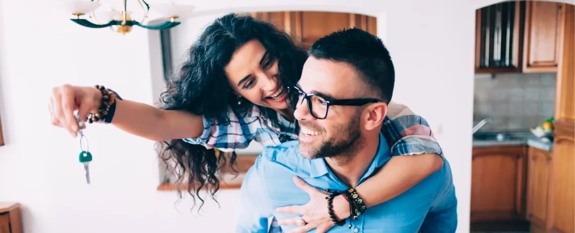 Deux personnes à l’intérieur d’un logement, l’une tenant un trousseau de clés au premier plan, dans une pièce aménagée.