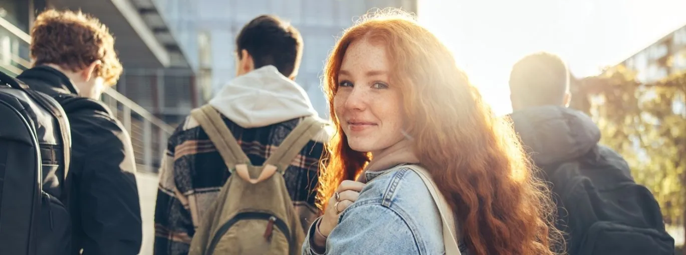 Jeune fille en premier plan avec 3 garçons de dos marchant.