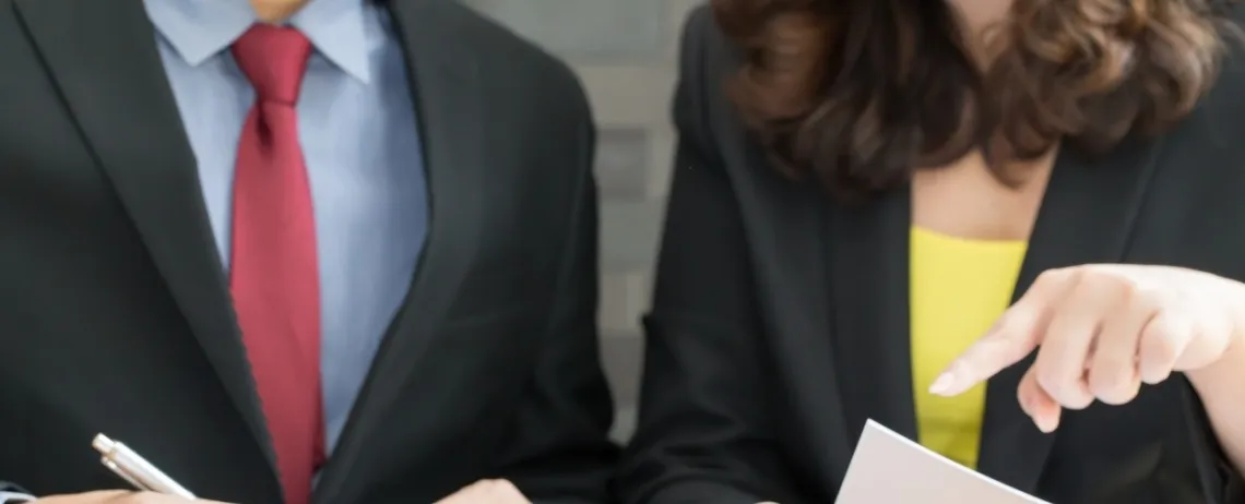 Deux professionnels examinent un document, l’un pointant une information.
