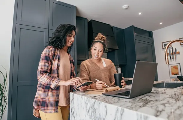 deux jeunes femmes font des calculs sur le plan de travail dans leur cuisine