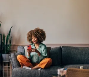 Jeune femme sur son canapé qui regarde son téléphone portable