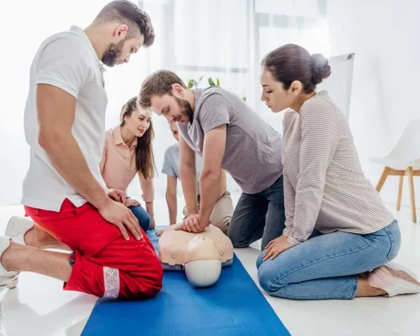 Groupe de personnes pratiquent les gestes de réanimation cardio‑pulmonaire sur un mannequin lors d’une formation aux premiers secours, dans une salle lumineuse.