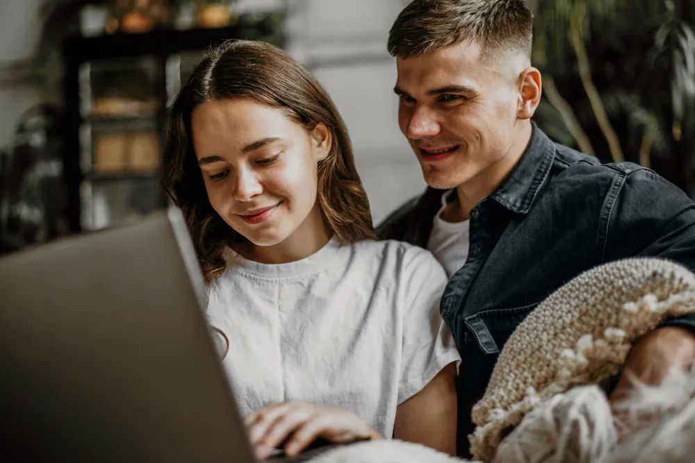 jeune couple devant un ordinateur sur le canapé